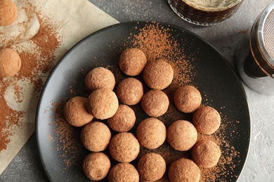 Photo of Plate with chocolate truffles on grey background, top view