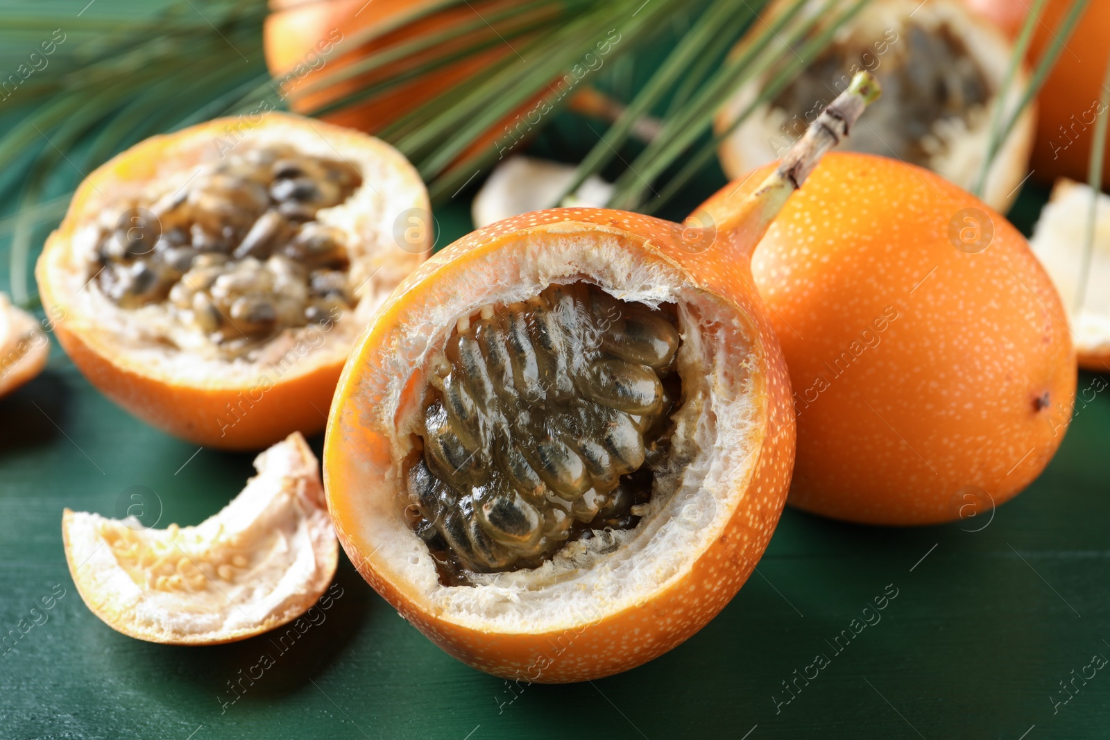 Photo of Delicious ripe granadillas on green wooden table, closeup