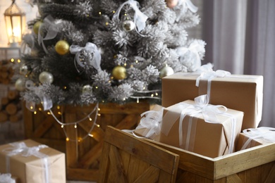 Decorated Christmas tree and gift boxes In elegant room interior
