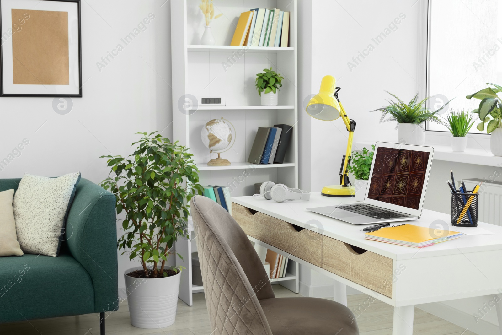 Photo of Cozy workspace with modern laptop on white wooden desk and comfortable chair at home