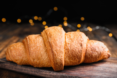 Tasty fresh croissant on wooden table, closeup