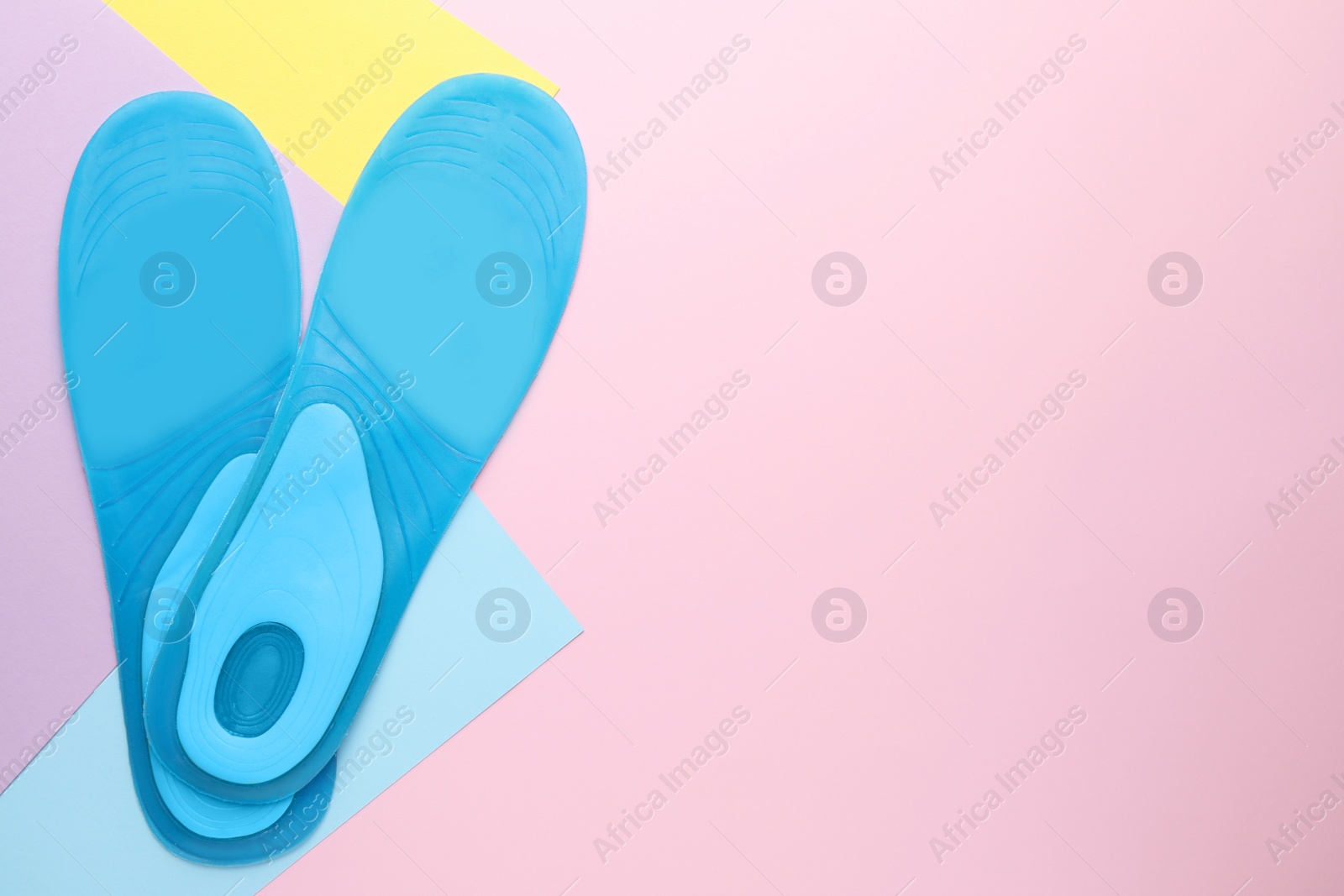 Photo of LIght blue orthopedic insoles on color background, flat lay. Space for text