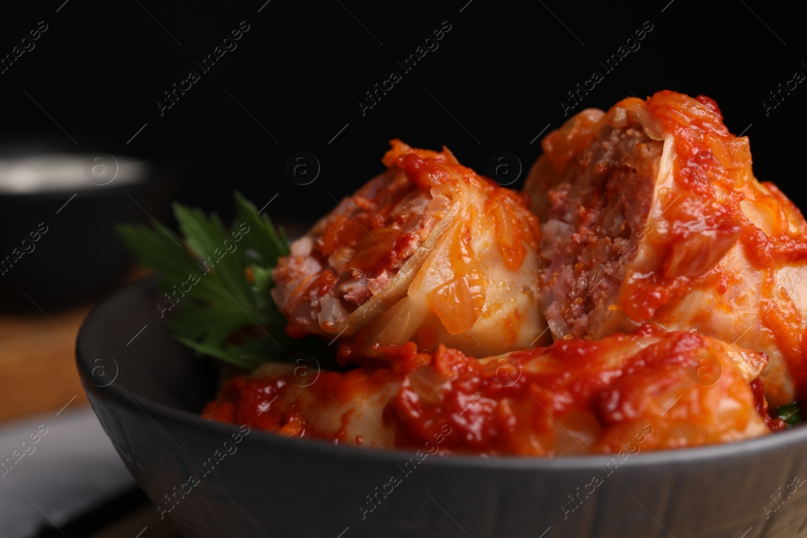 Photo of Delicious stuffed cabbage rolls cooked with homemade tomato sauce in bowl, closeup