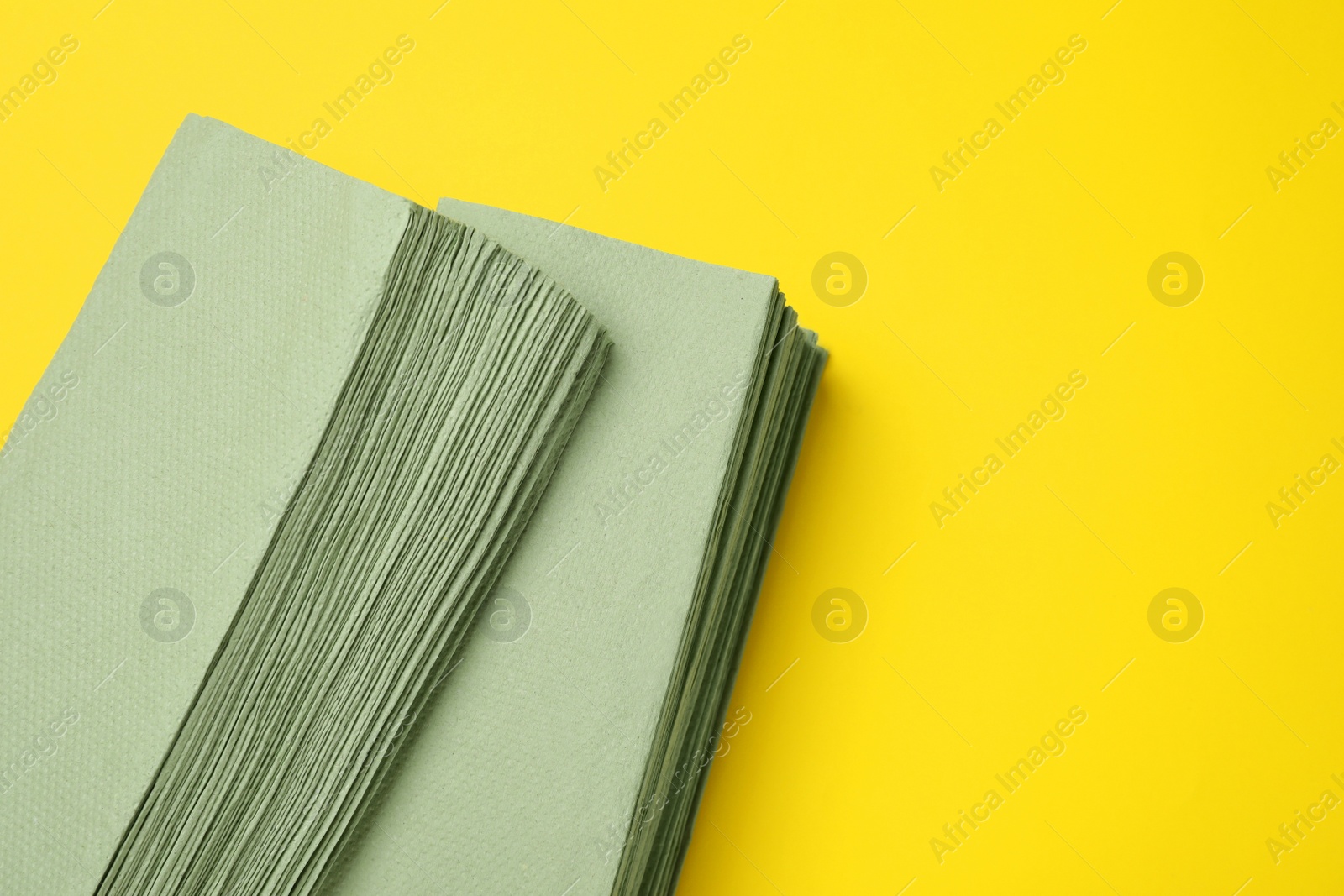 Photo of Green paper towels on yellow background, above view. Space for text