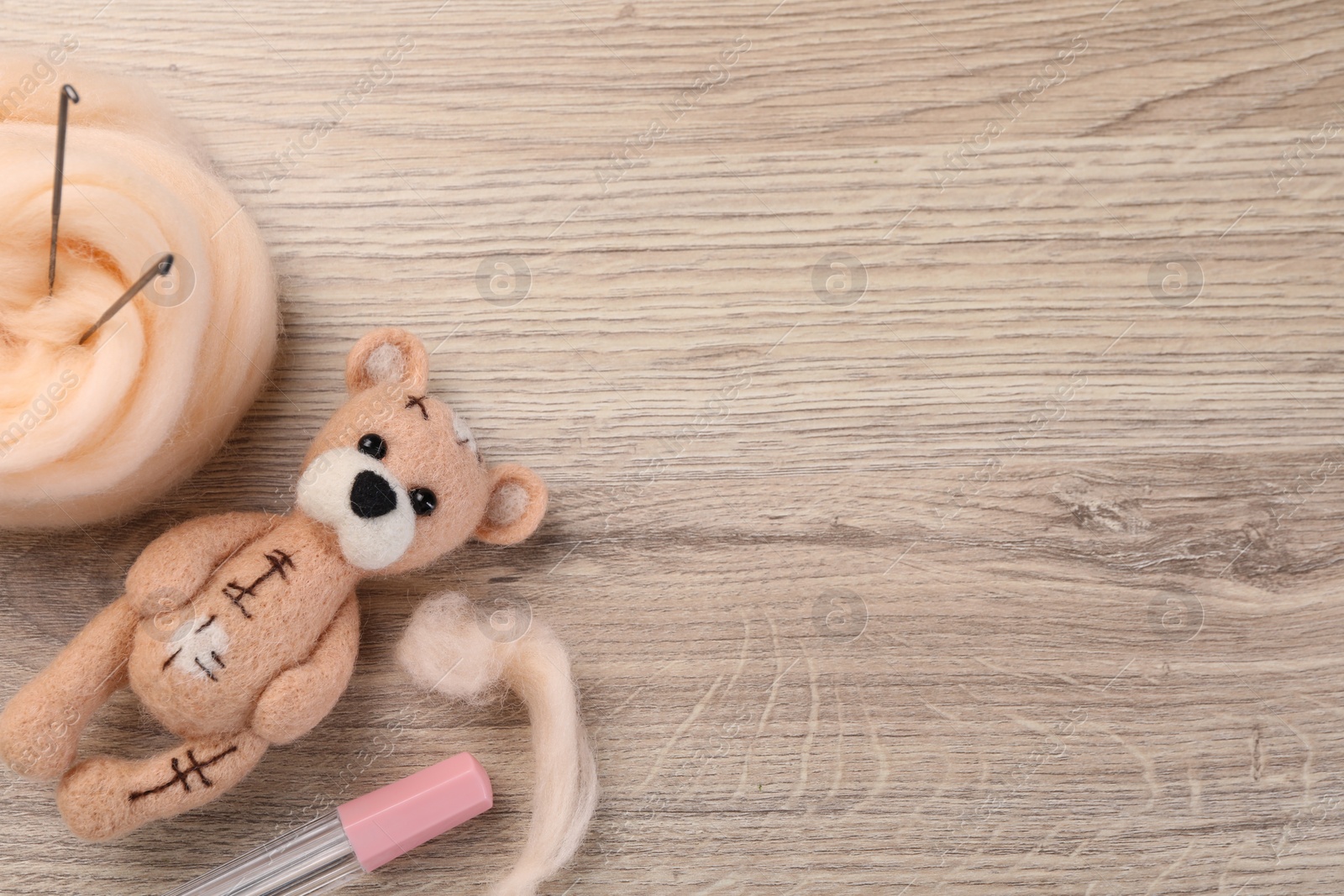 Photo of Felted bear, wool and tools on wooden table, flat lay. Space for text