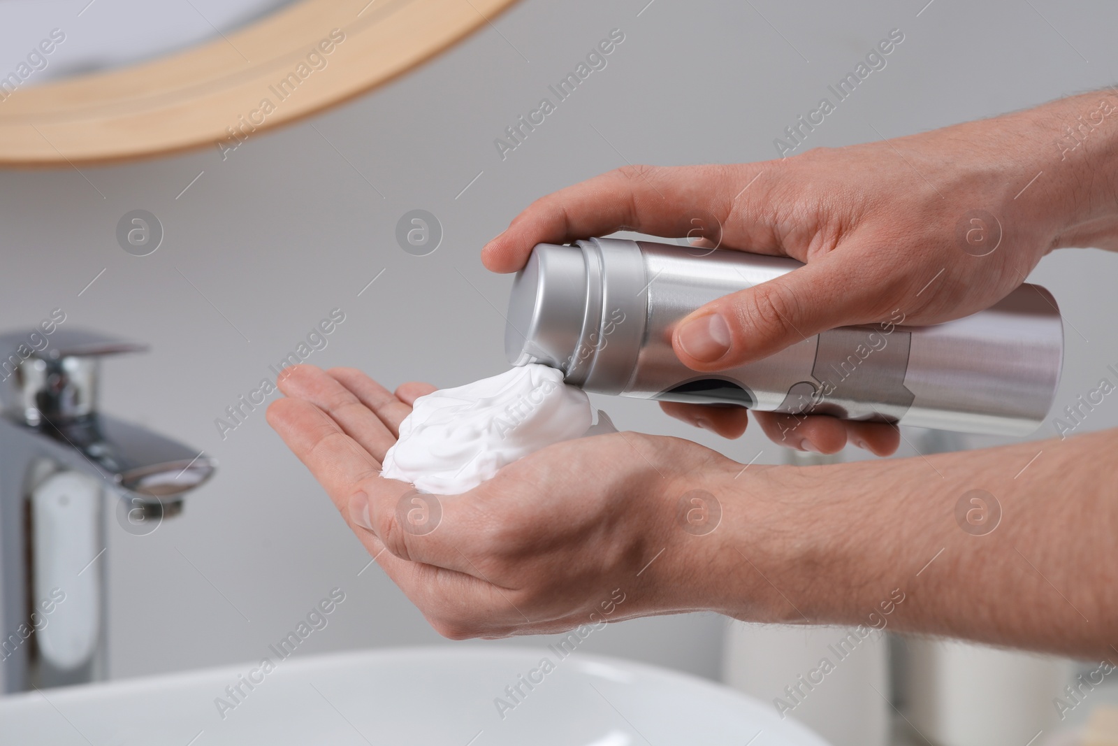 Photo of Man applying shaving foam onto hand in bathroom, closeup