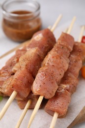 Wooden skewers with cut raw marinated meat on table, closeup