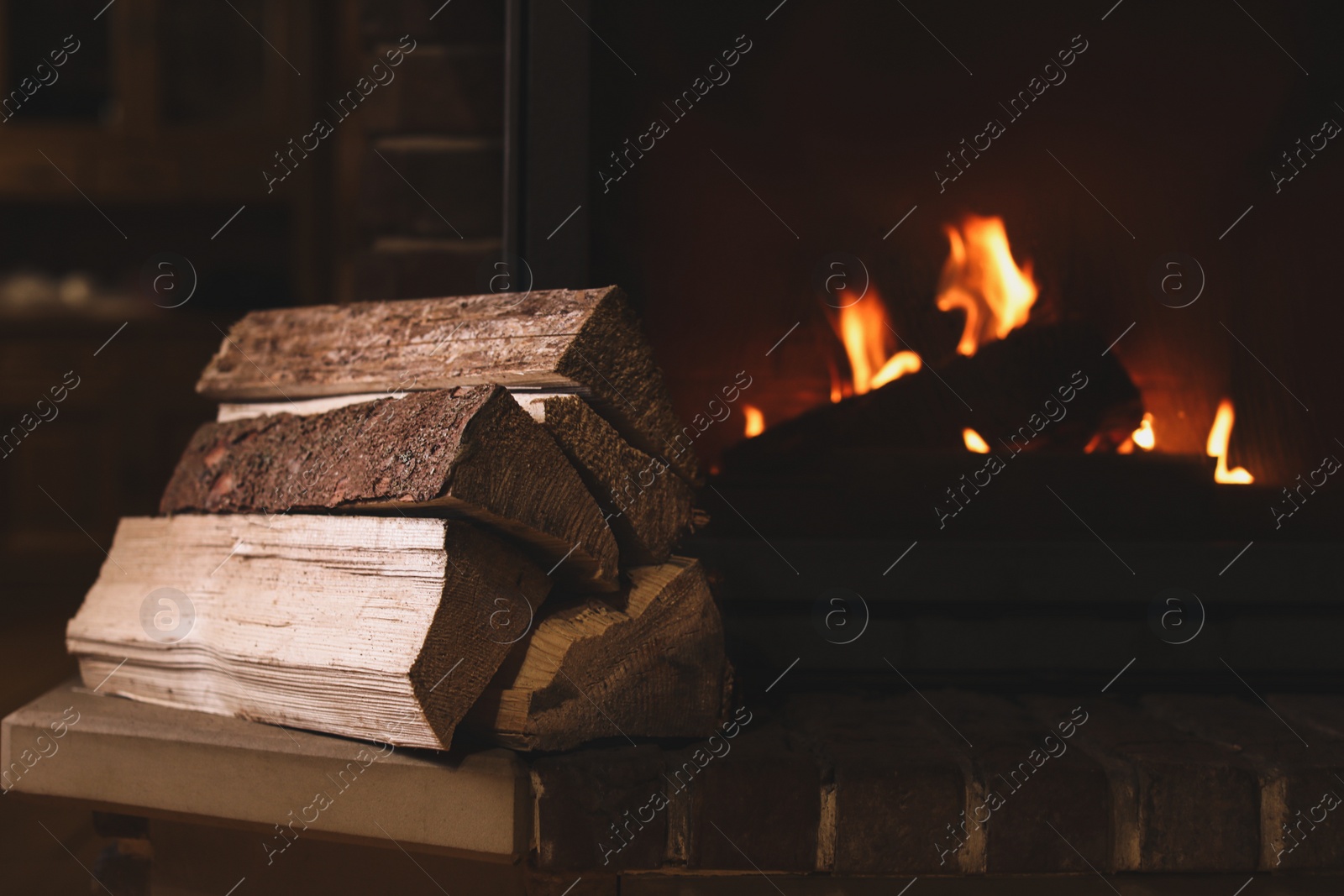 Photo of Pile of wood near fireplace indoors. Winter vacation