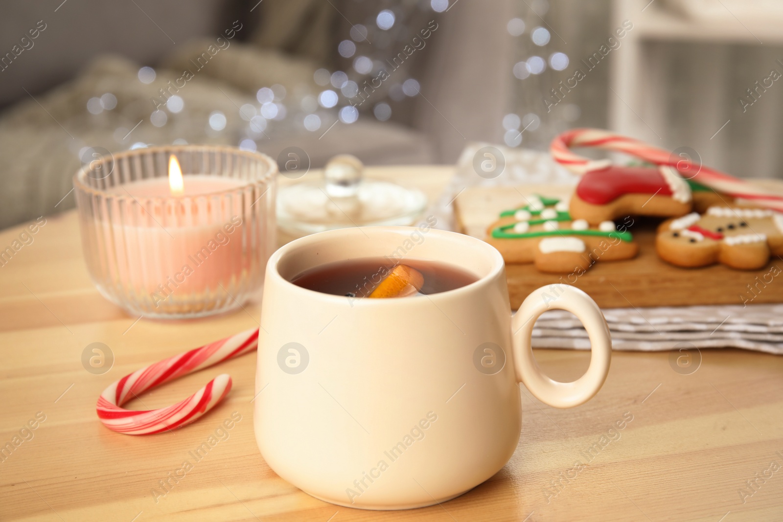 Photo of Cup of hot mulled wine on wooden table indoors. Winter drink