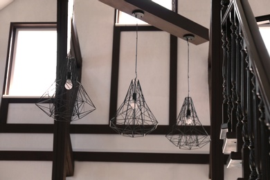 Stylish metal pendant lamps with light bulbs indoors