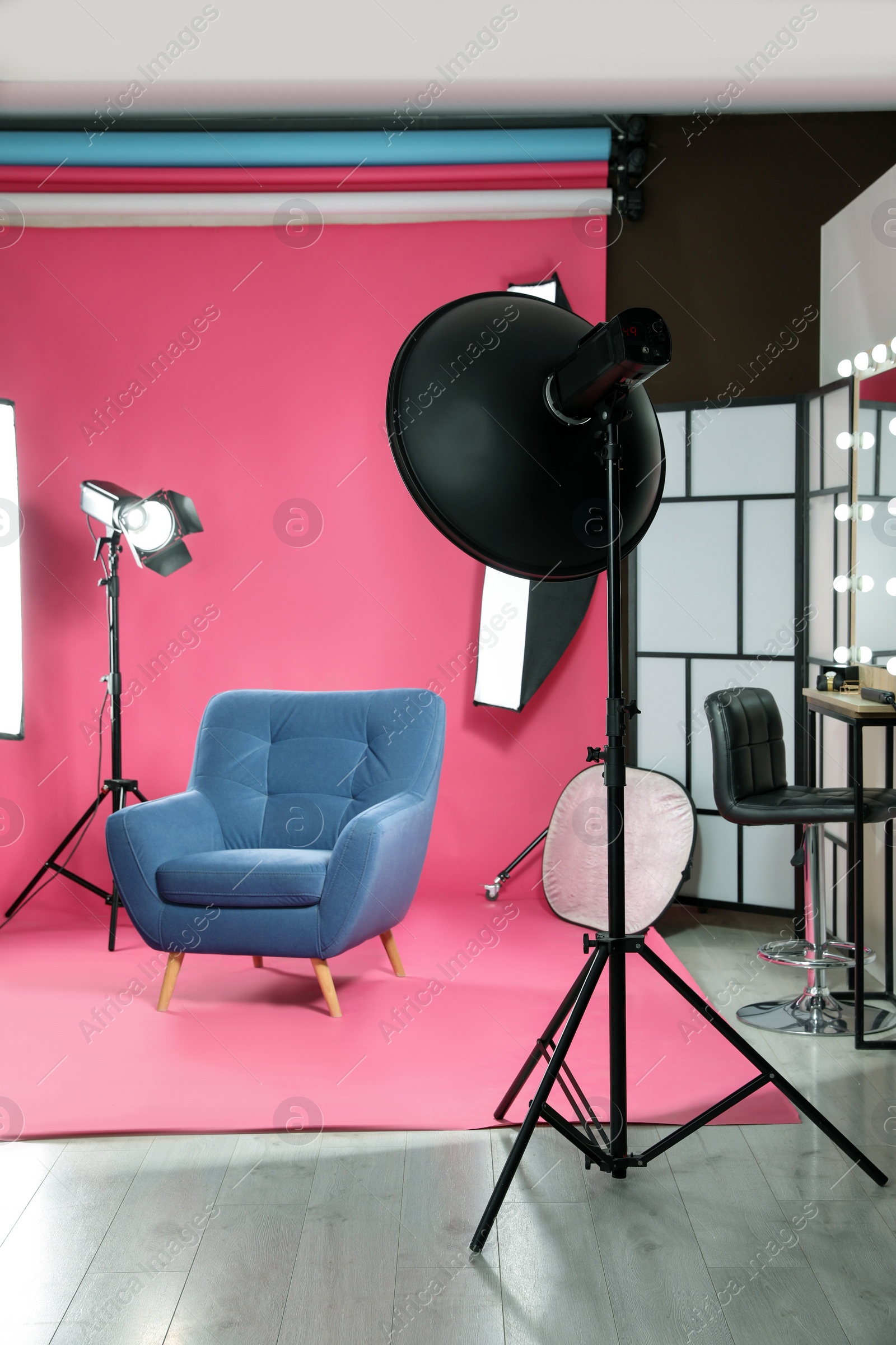 Photo of Stylish blue armchair in photo studio with professional equipment