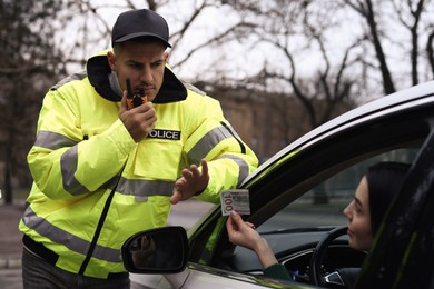 Photo of Police officer rejecting bribe near car outdoors