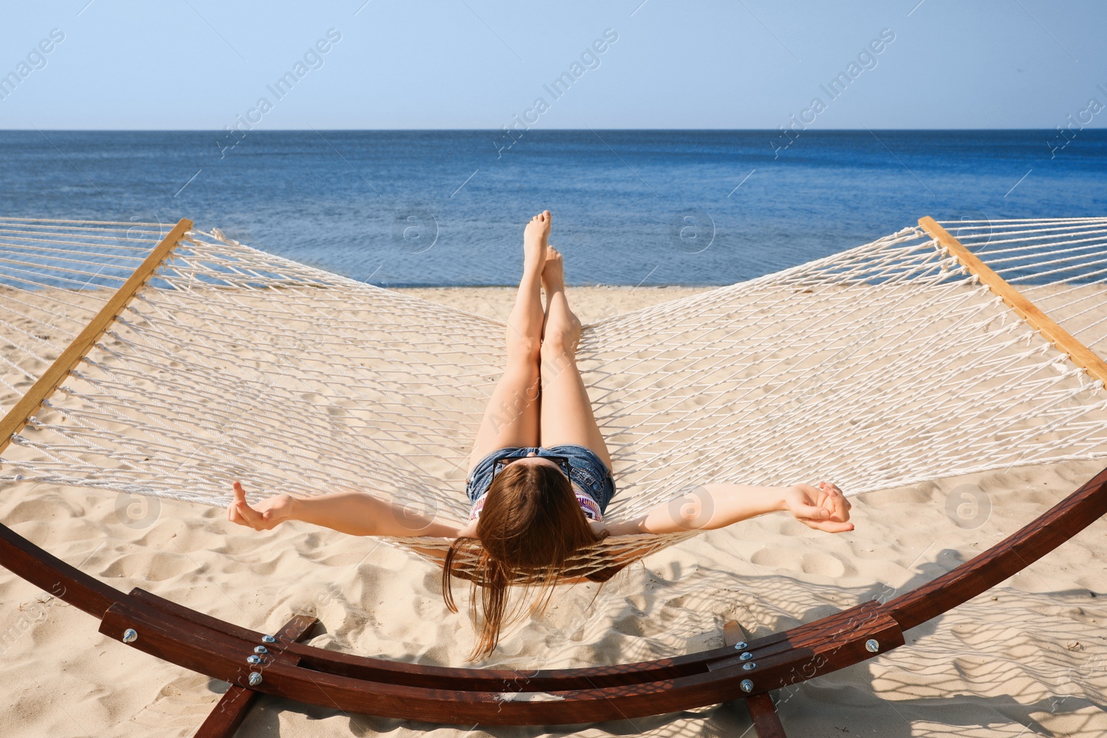 Photo of Young woman relaxing in hammock on beach