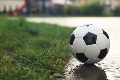 Wet leather soccer ball on street, space for text