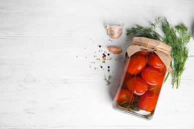 Photo of Flat lay composition with pickled tomatoes in glass jar on white wooden table, space for text