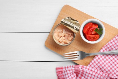 Photo of Can of conserved tuna and tomatoes on white wooden table, top view. Space for text