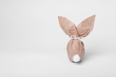 Easter bunny made of kraft paper and egg on white background. Space for text
