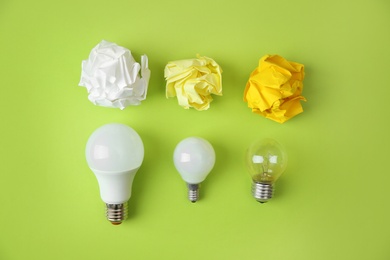 Photo of Flat lay composition with lamp bulbs and crumpled paper on color background