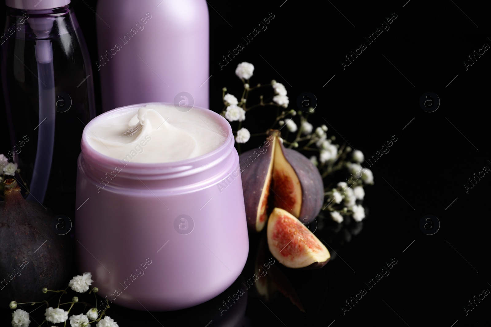 Photo of Set of hair cosmetic products, flowers and figs on  black background, closeup