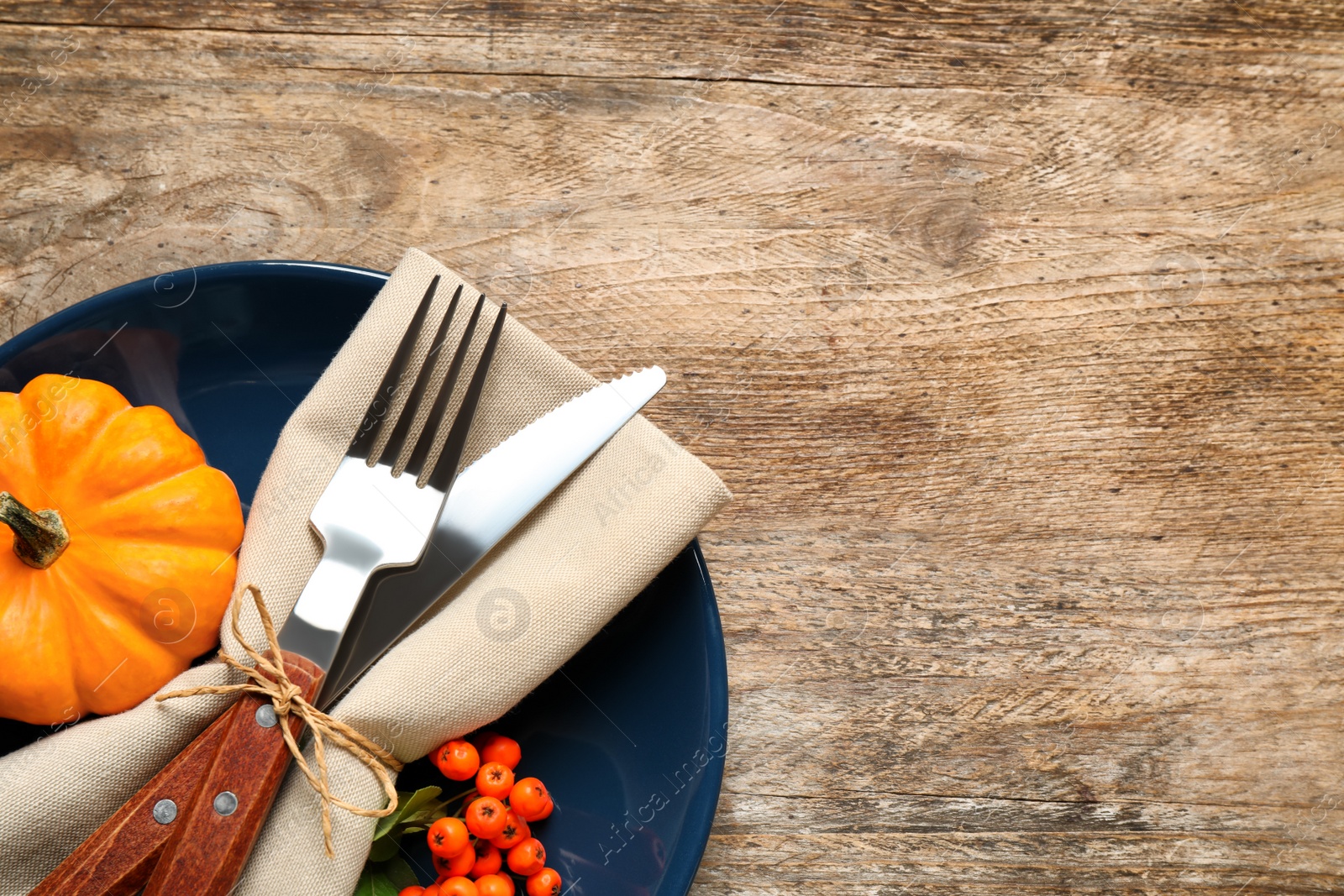 Photo of Top view of seasonal table setting with ashberries and pumpkin on wooden background, space for text. Thanksgiving Day