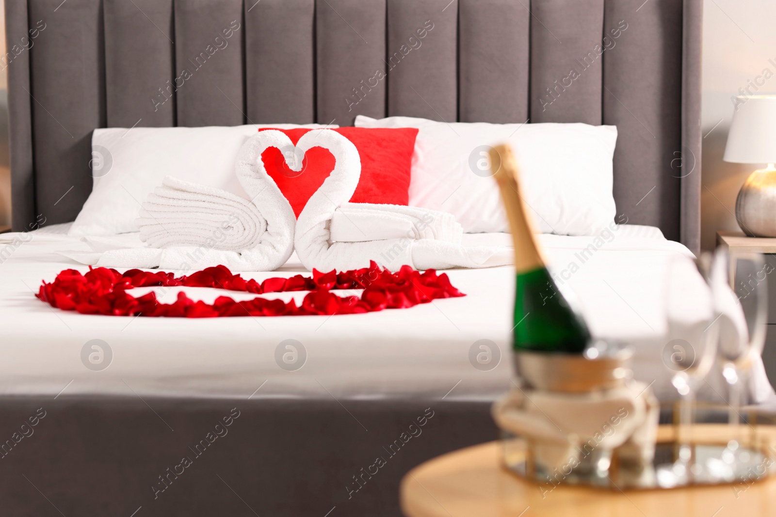 Photo of Honeymoon. Swans made with towels and beautiful rose petals on bed in room