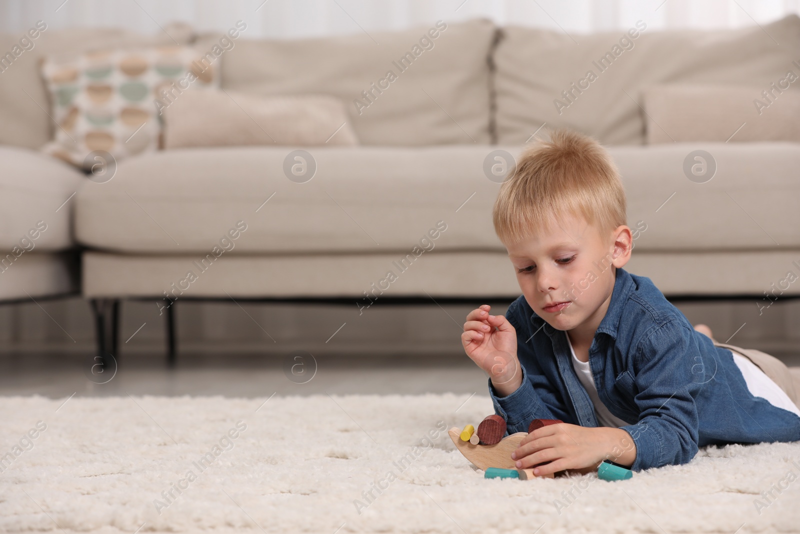 Photo of Cute little boy playing with wooden balance toy on carpet indoors, space for text