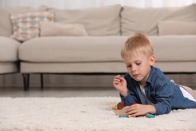 Cute little boy playing with wooden balance toy on carpet indoors, space for text