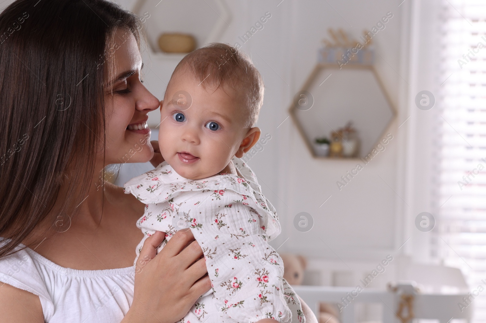 Photo of Happy young mother with her baby daughter in nursery. Space for text