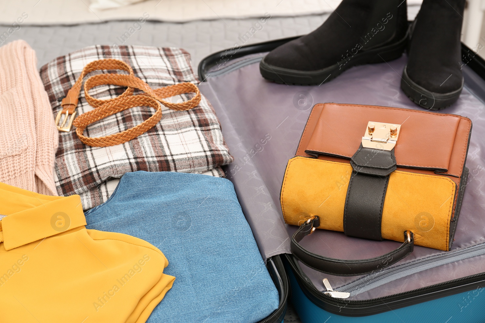 Photo of Packed suitcase with clothes, shoes and accessories, closeup