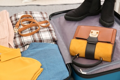 Packed suitcase with clothes, shoes and accessories, closeup