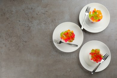 Delicious broken glass jelly dessert on grey table, flat lay. Space for text