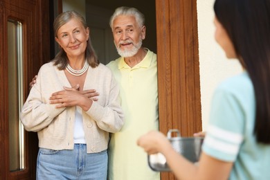 Photo of Friendly relationship with neighbours. Young woman with saucepan visiting elderly couple