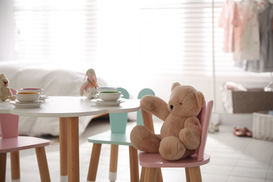 Photo of Small table and chairs with bunny ears in children's room interior