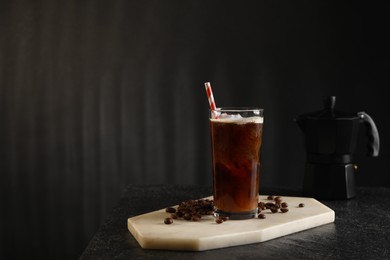 Photo of Refreshing iced coffee with milk in glass and beans on table against dark gray background, space for text