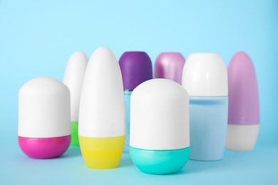 Photo of Set of different female roll-on deodorants on light blue background