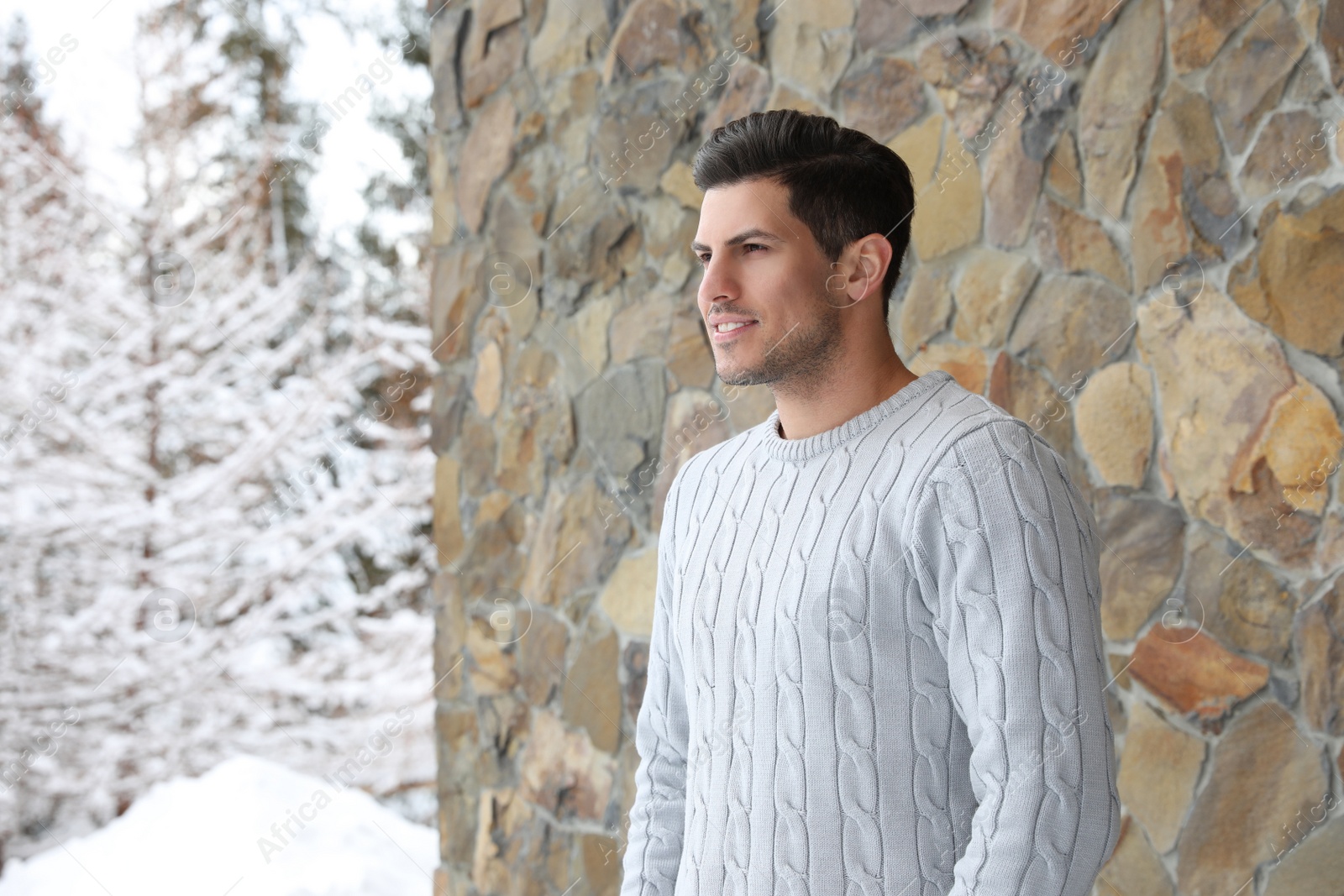 Photo of Happy man in warm sweater near stone wall outdoors