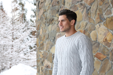 Photo of Happy man in warm sweater near stone wall outdoors