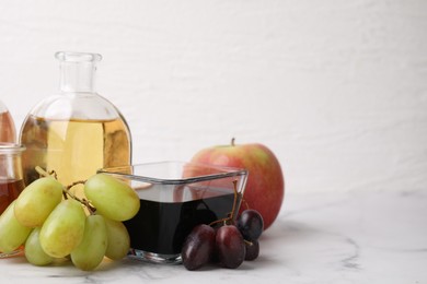 Photo of Different types of vinegar and ingredients on light marble table, closeup. Space for text