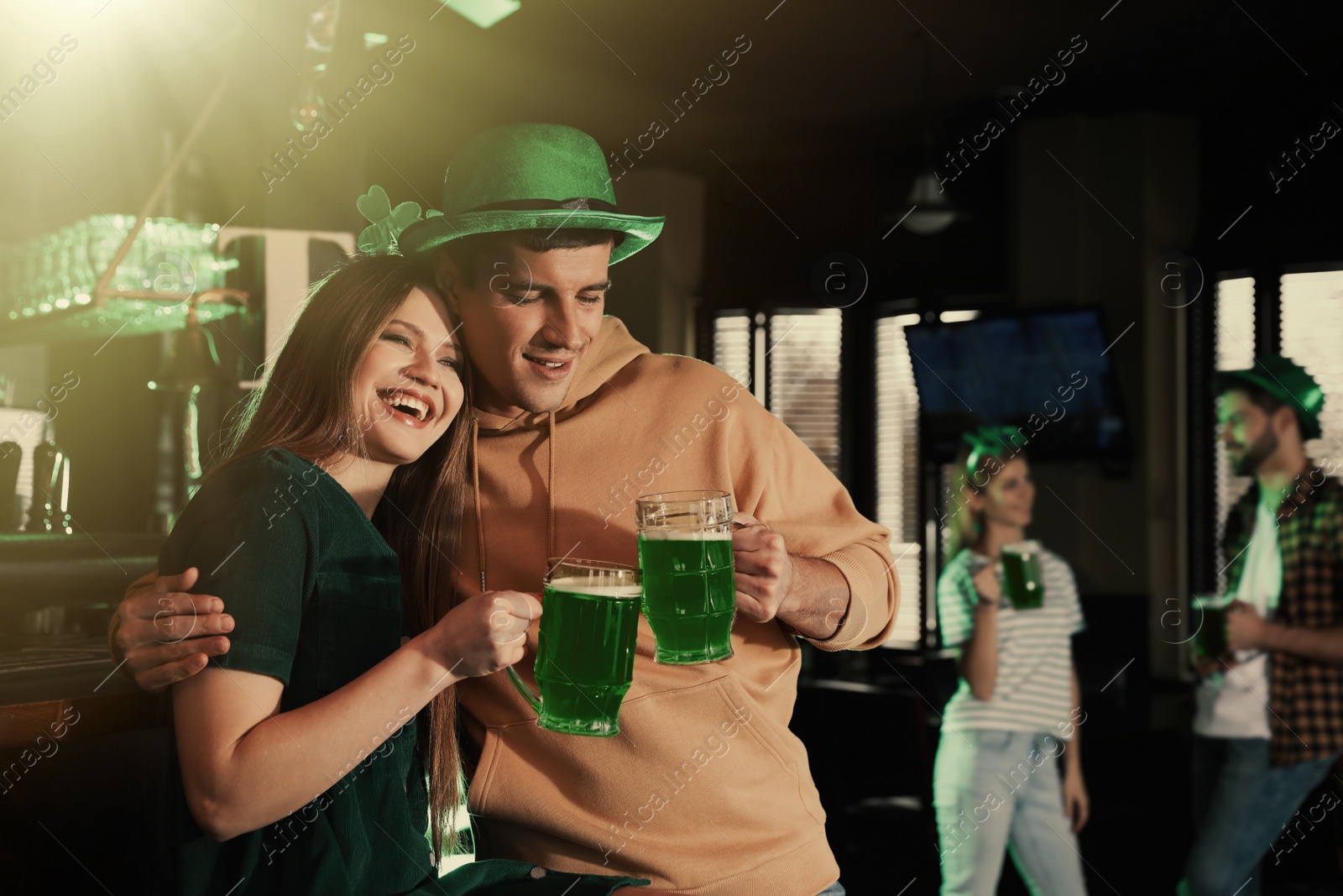 Photo of Young woman and man toasting with green beer in pub. St. Patrick's Day celebration