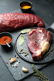 Photo of Pieces of raw beef meat and spices on black table