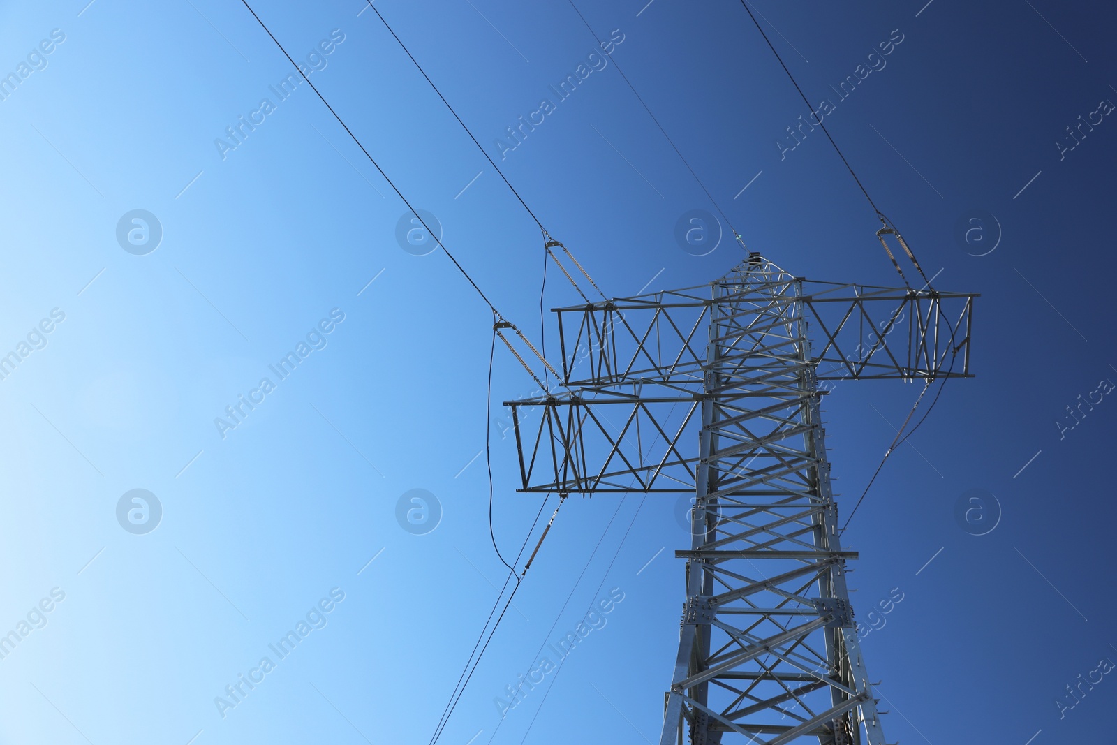 Photo of Modern high voltage tower against blue sky, low angle view