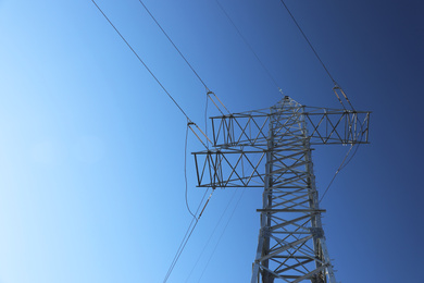 Modern high voltage tower against blue sky, low angle view