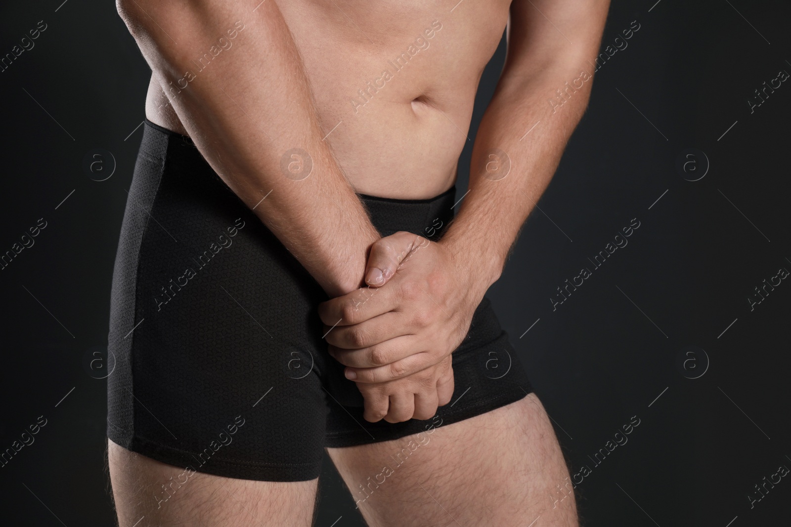 Photo of Man suffering from pain on black background, closeup. Urology problems