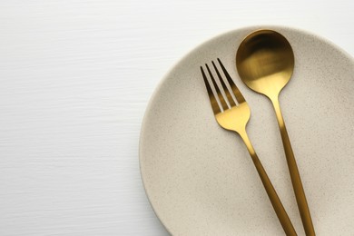 Photo of Clean plate, fork and spoon on white table, top view. Space for text