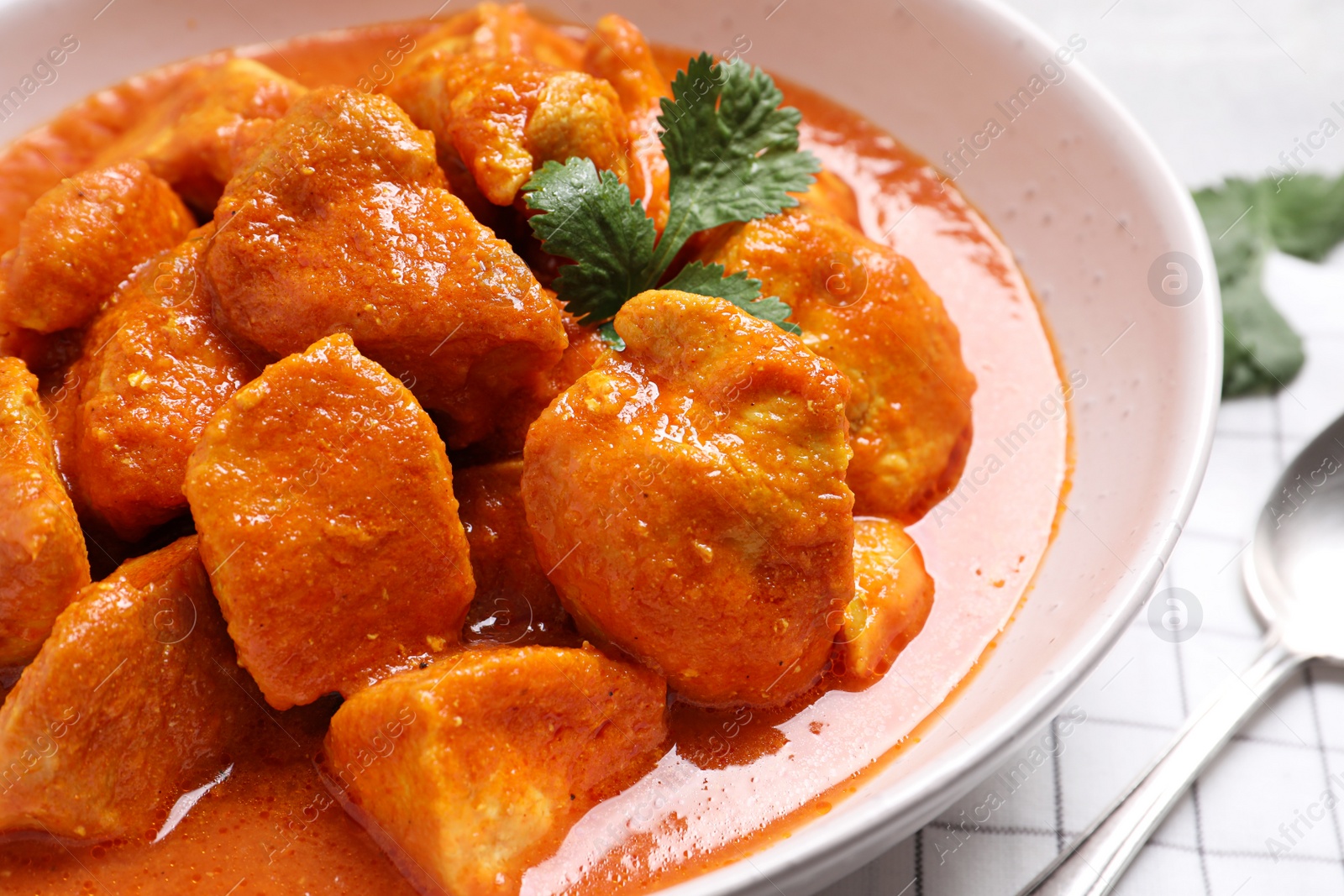 Photo of Bowl of delicious chicken curry on table, closeup