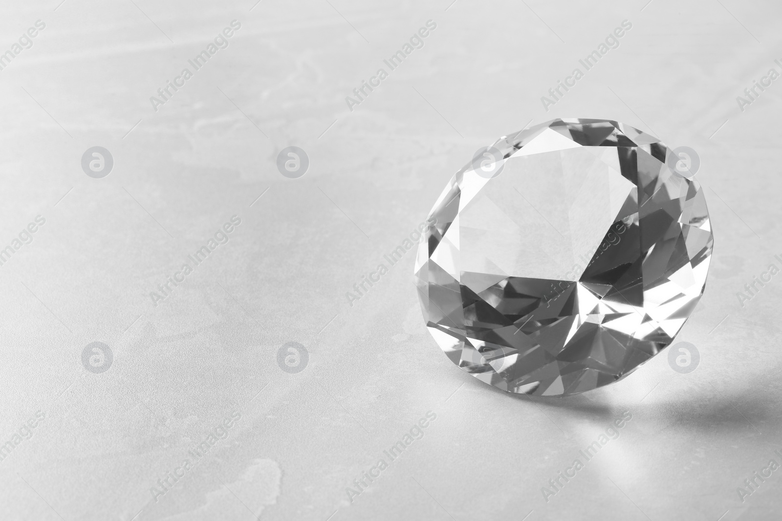 Photo of Beautiful shiny diamond on gray table, closeup. Space for text