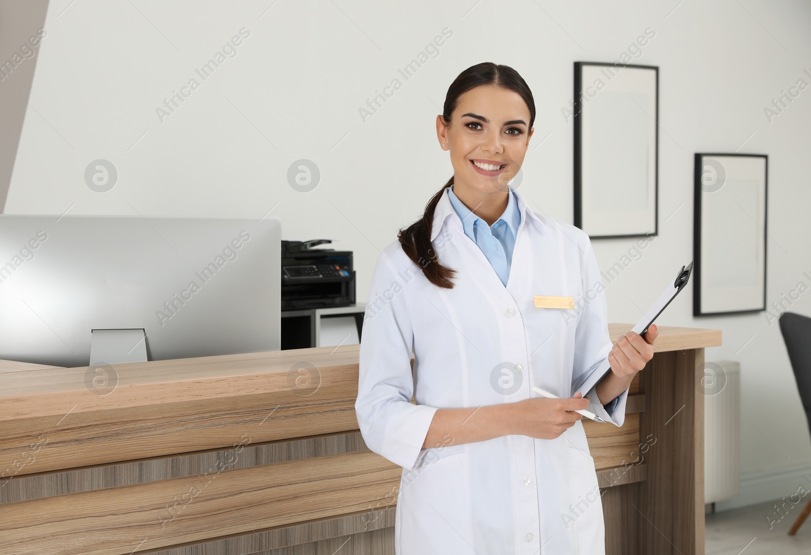 Photo of Portrait of receptionist with clipboard near desk in modern clinic