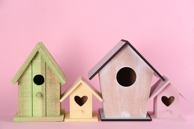 Photo of Collection of handmade bird houses on pink background