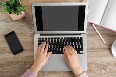 Photo of Woman working with laptop at table, top view. Space for design