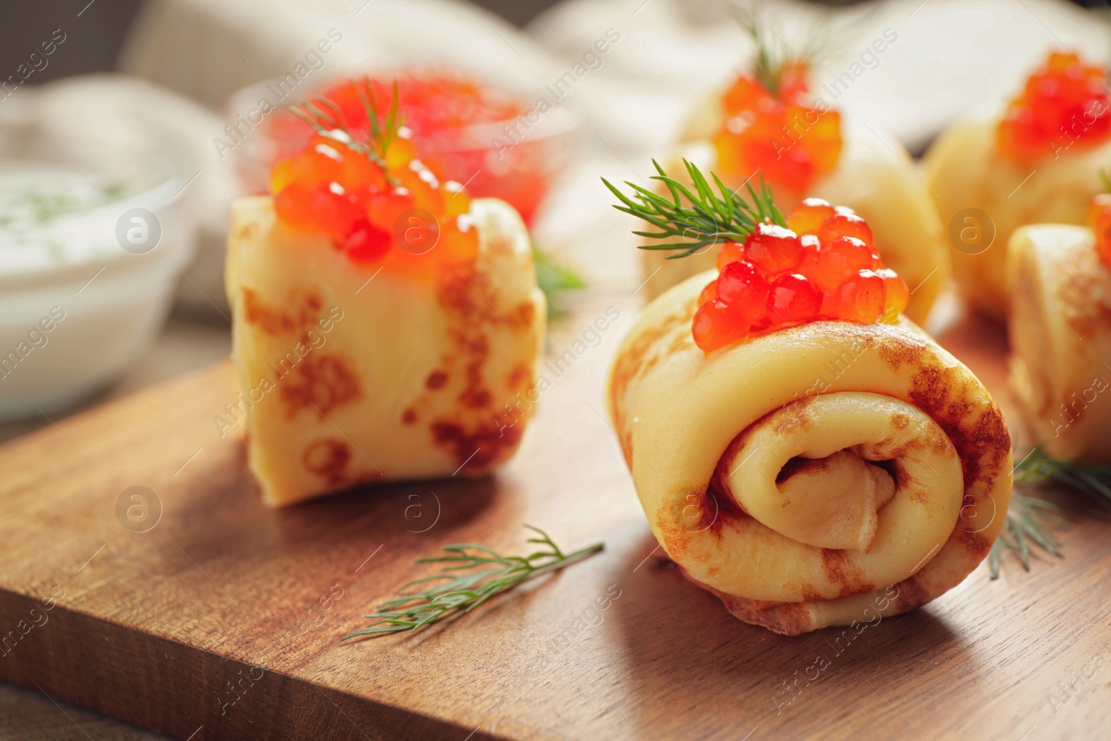 Photo of Delicious thin pancakes with red caviar on wooden board, closeup